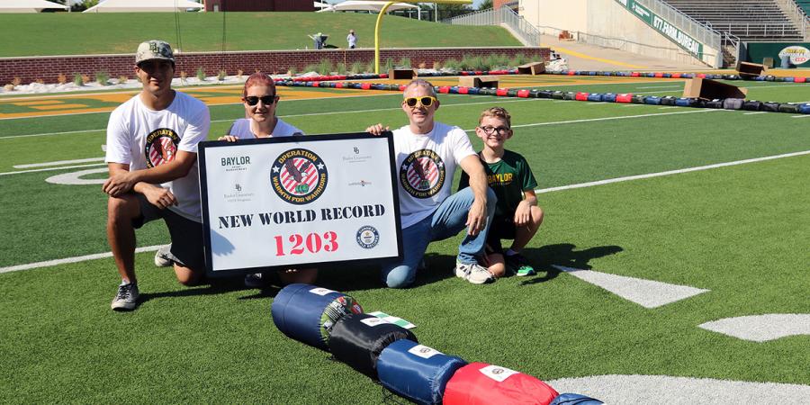 Volunteers with the Guinness World Record sign on the field at McLane Stadium