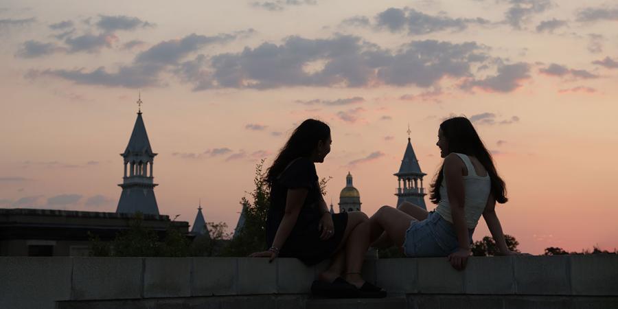Two students overlooking the campus skyline at dusk