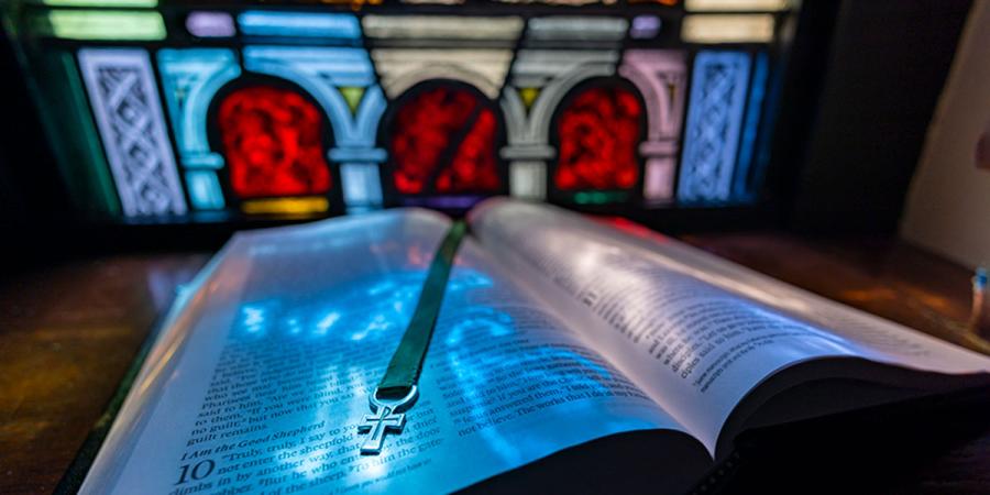 An open Bible in front of stained glass in a Baylor chapel