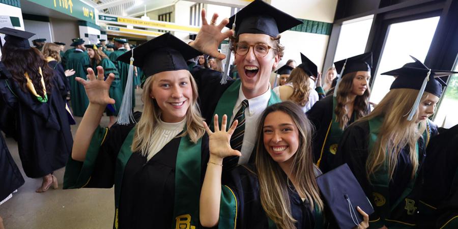 Three new Baylor graduates do a 'sic 'em' in the Ferrell Center corridor