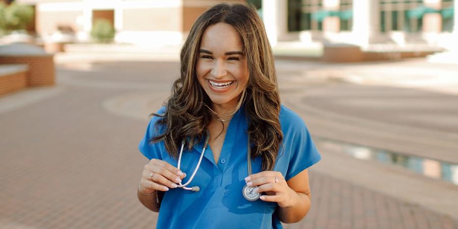 Kayla Carmer in scrubs outside the Baylor Sciences Building