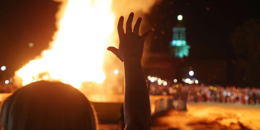 A "sic 'em" hand in silhouette against the bonfire