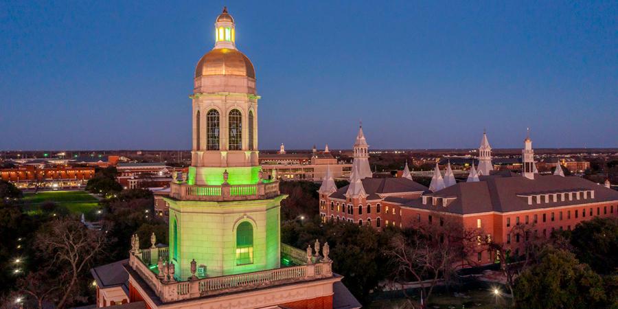 Pat Neff Hall lit green over campus