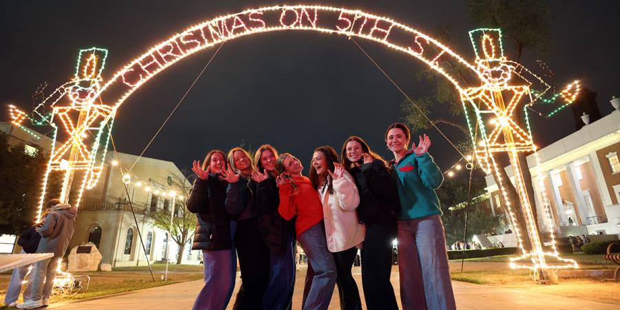 Students pose with the Christmas on 5th Street lighted arch