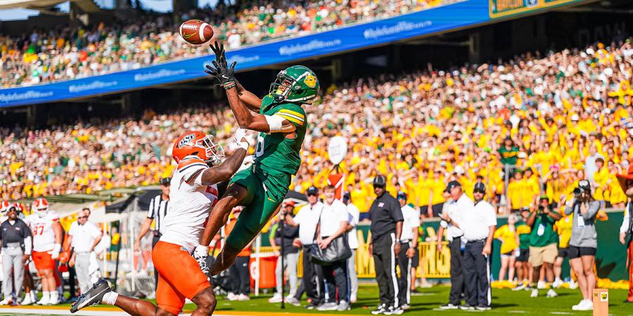 A Baylor wide receiver makes a jumping catch in front of a large Baylor crowd