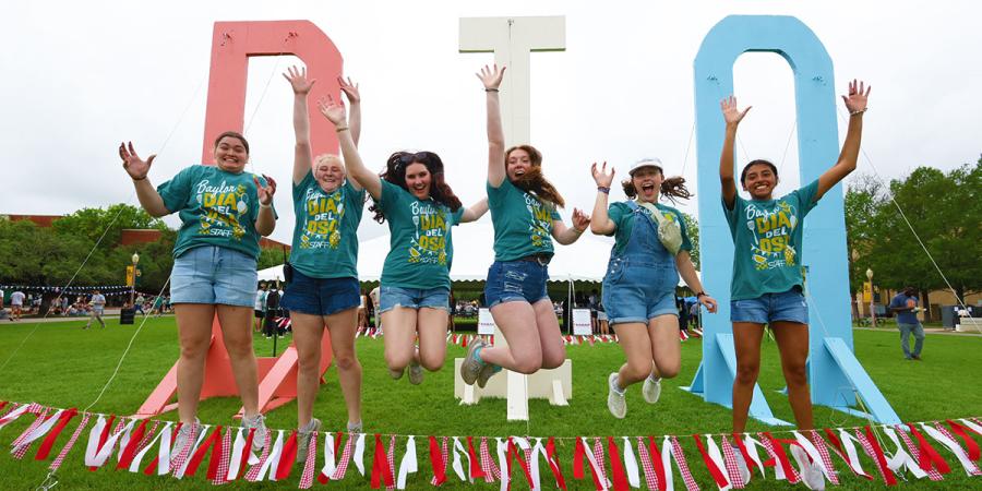 Students jump in front of the large DIA letters on Fountain Mall