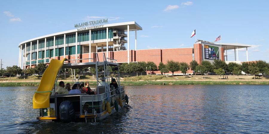 Fans sailgate in a boat outside McLane Stadium