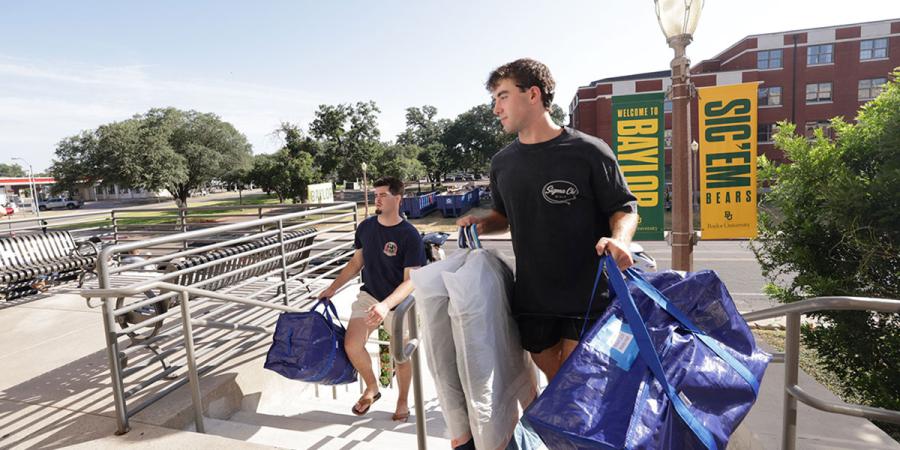 Baylor student volunteers carry another student's items into Martin Hall
